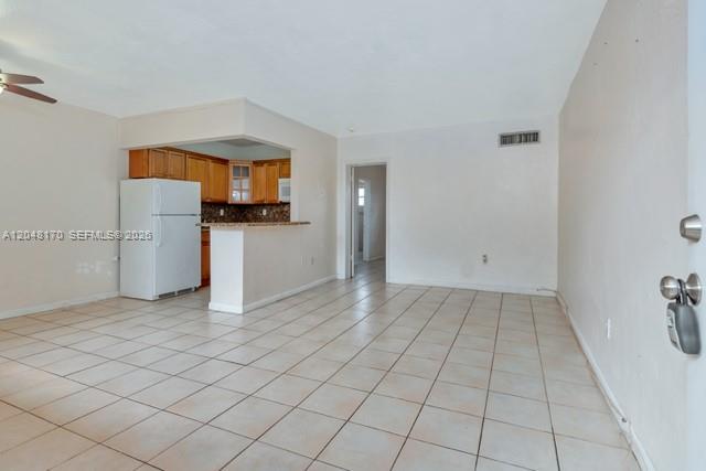 An open-concept living area features light tile flooring and a kitchen with wood cabinets — 1280 W 54th St # 313B, Hialeah FL 33012, HIALEAH, FL