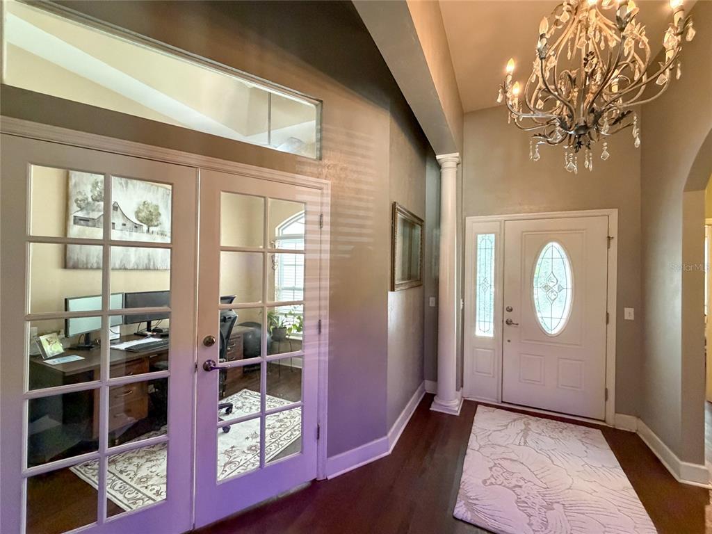 An entryway features a chandelier, a white front door, and French doors leading to an office — 20942 NW 200TH AVENUE, HIGH SPRINGS, FL