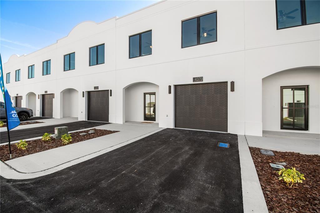 A row of modern white townhouses features dark garage doors and paved driveways — 4350 CAMBIO GARDENS COURT, TAMPA, FL