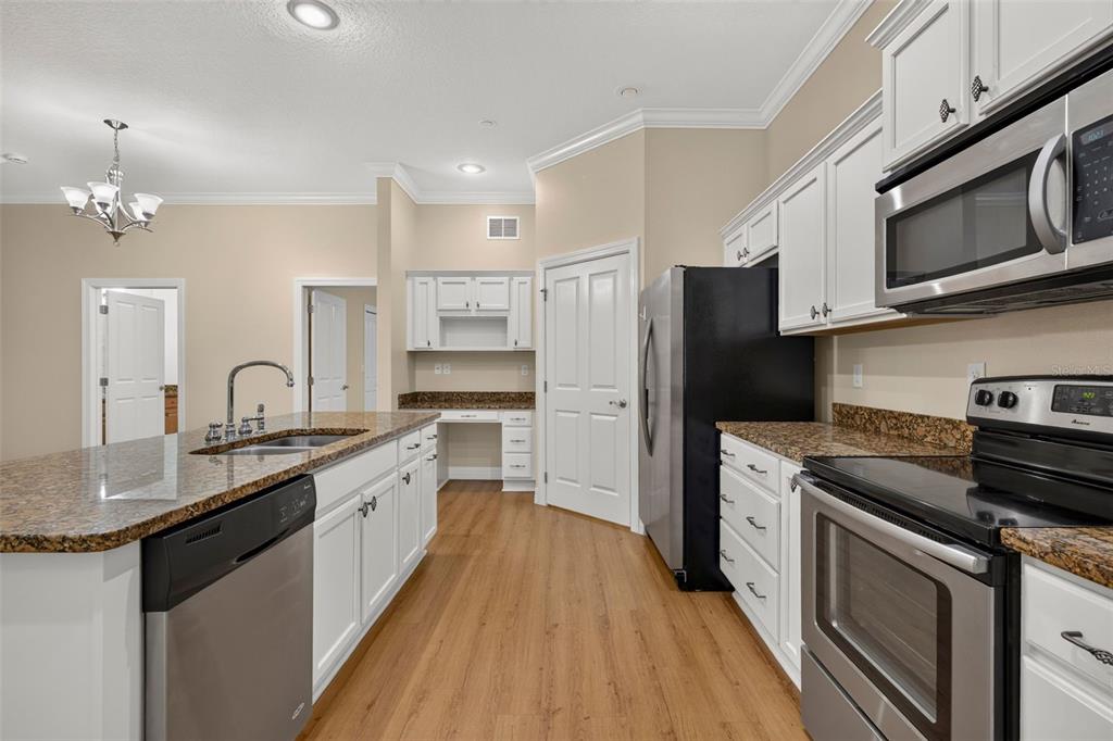 A kitchen features white cabinets, granite countertops, stainless steel appliances, and a central island — 7980 SOUTHERN PINES DRIVE, BROOKSVILLE, FL