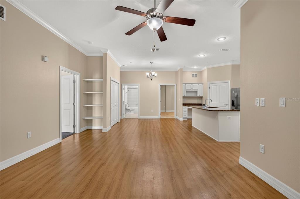 An open-concept living area with wood-look flooring, a ceiling fan, and an adjacent kitchen — 7980 SOUTHERN PINES DRIVE, BROOKSVILLE, FL