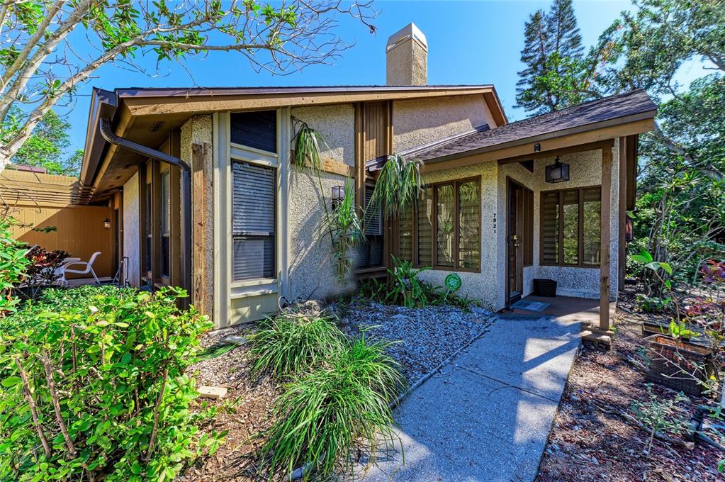 The exterior of a single-story house features textured stucco walls, brown trim, and a chimney — 7921 4TH AVENUE W, BRADENTON, FL