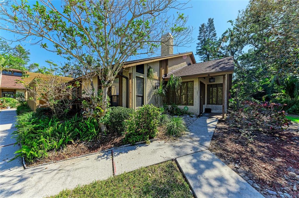 A tan stucco house with a brown shingled roof and a concrete walkway — 7921 4TH AVENUE W, BRADENTON, FL