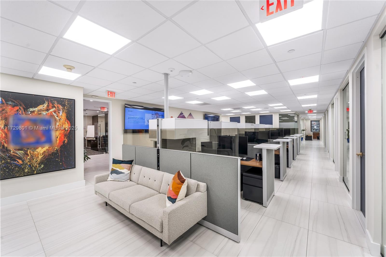 An office interior features a grey sofa, cubicle workstations, and white tile flooring — 1200 Brickell Ave # A, Miami FL 33131, MIAMI, FL