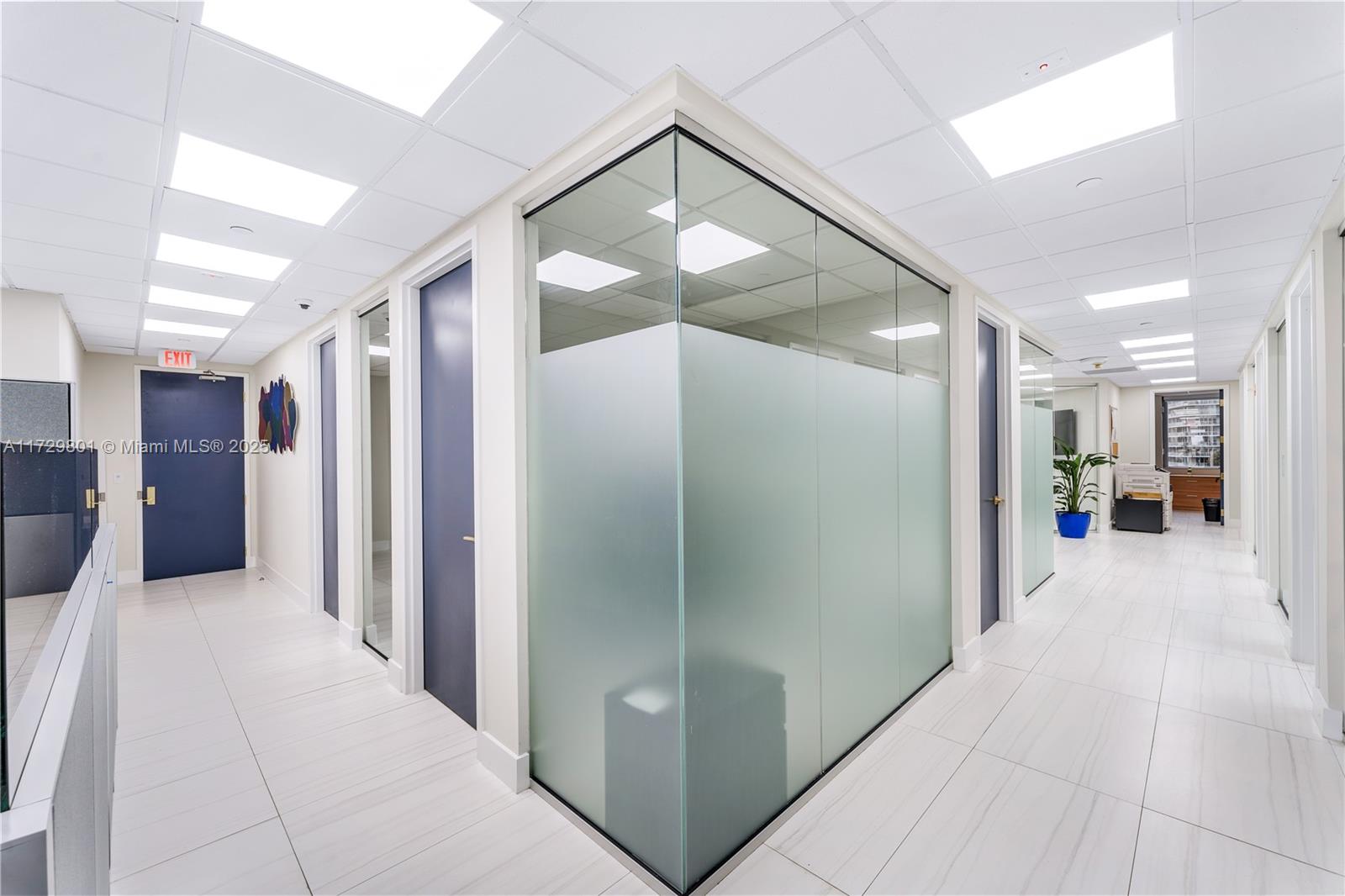 A modern office hallway features white tiled floors, glass-walled partitions, and dark blue doors — 1200 Brickell Ave # A, Miami FL 33131, MIAMI, FL