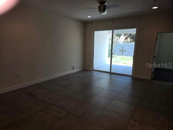 An empty room with tile flooring, a ceiling fan, and sliding glass doors to a patio — 922 CENTAURY DRIVE, KISSIMMEE, FL
