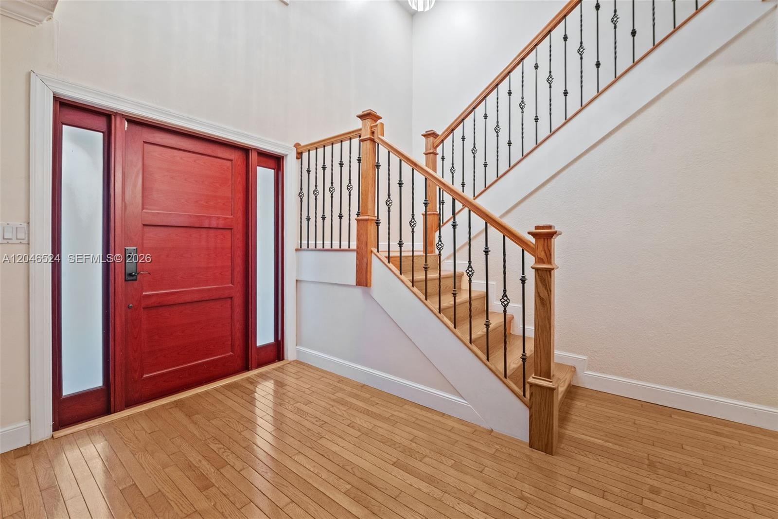 An entryway features a red wooden door, hardwood floors, and a staircase with iron railings — 1211 Algeria Ave, Coral Gables FL 33134, CORAL GABLES, FL