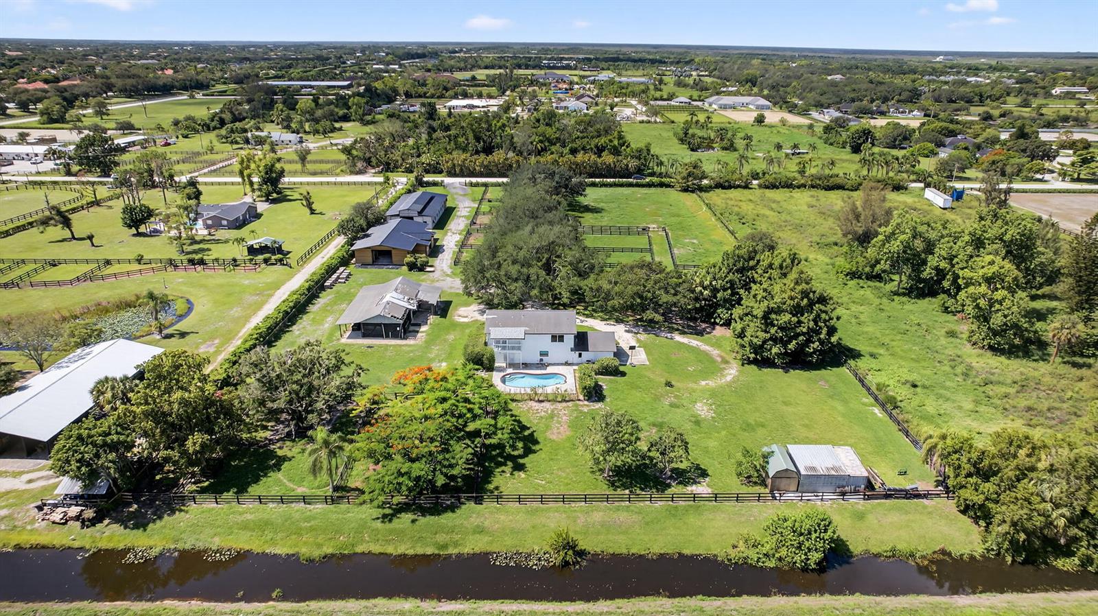 An aerial view shows a house with a pool, multiple outbuildings, and fenced pastures — 16229 Rustic Rd Road, Wellington FL 33470, WELLINGTON, FL