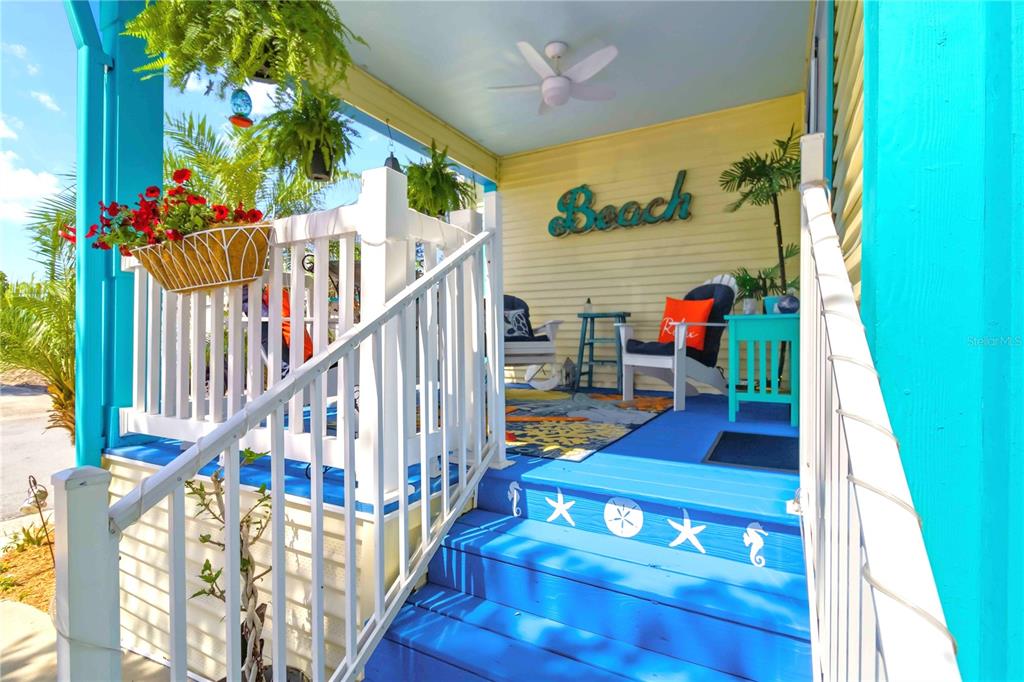 A bright blue and beige manufactured home features a front porch, palm trees, and carport — 915 50TH AVENUE W, BRADENTON, FL