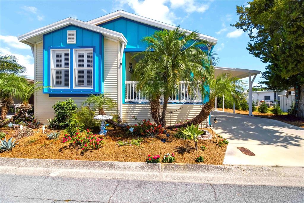 A covered porch features blue flooring, two chairs, a small table, and beach-themed decor — 915 50TH AVENUE W, BRADENTON, FL