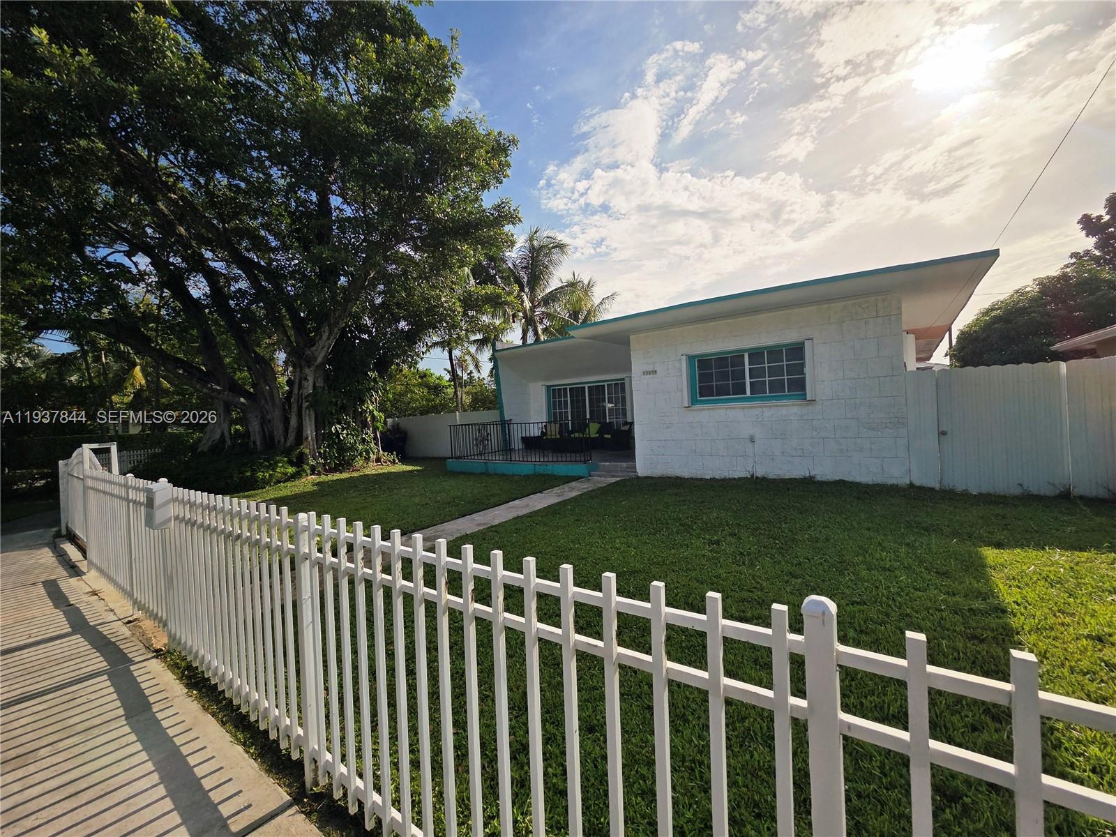 A white single-story house with a fenced yard and a large tree — 13895 NE 11th Ave, North Miami FL 33161, NORTH MIAMI, FL