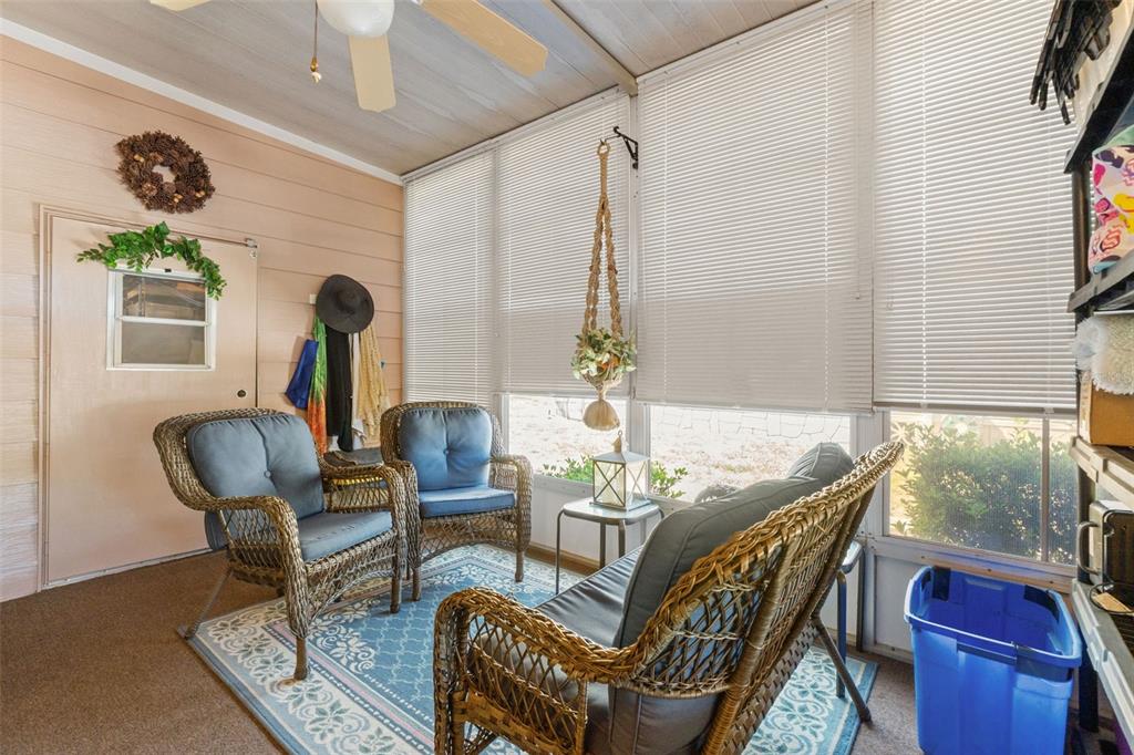 A sunroom features wicker furniture, a blue patterned rug, and large windows with white blinds — 15110 RIALTO AVENUE, BROOKSVILLE, FL