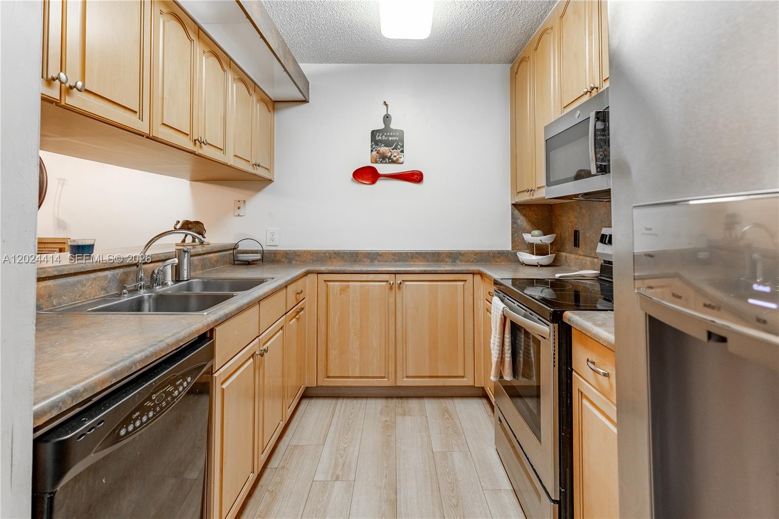 A galley kitchen features light wood cabinets, laminate countertops, and stainless steel appliances — 9135 SW 20th Pl, Davie FL 33324, DAVIE, FL