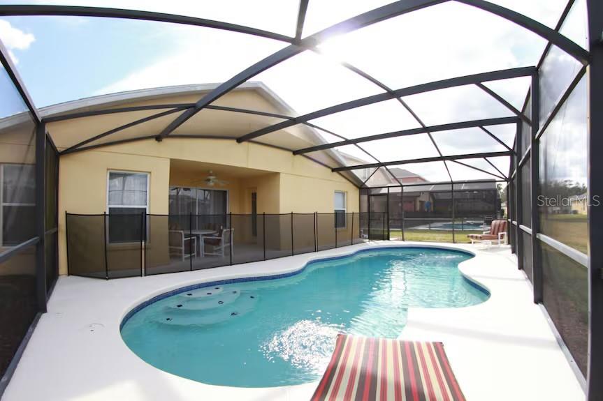 A screened-in patio features a swimming pool with steps and a black safety fence — 136 STARBIRD COURT, DAVENPORT, FL