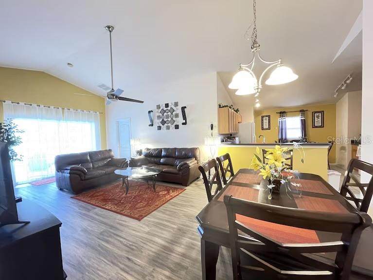 An open-concept living and dining area features wood-look flooring, a ceiling fan, and yellow walls — 136 STARBIRD COURT, DAVENPORT, FL