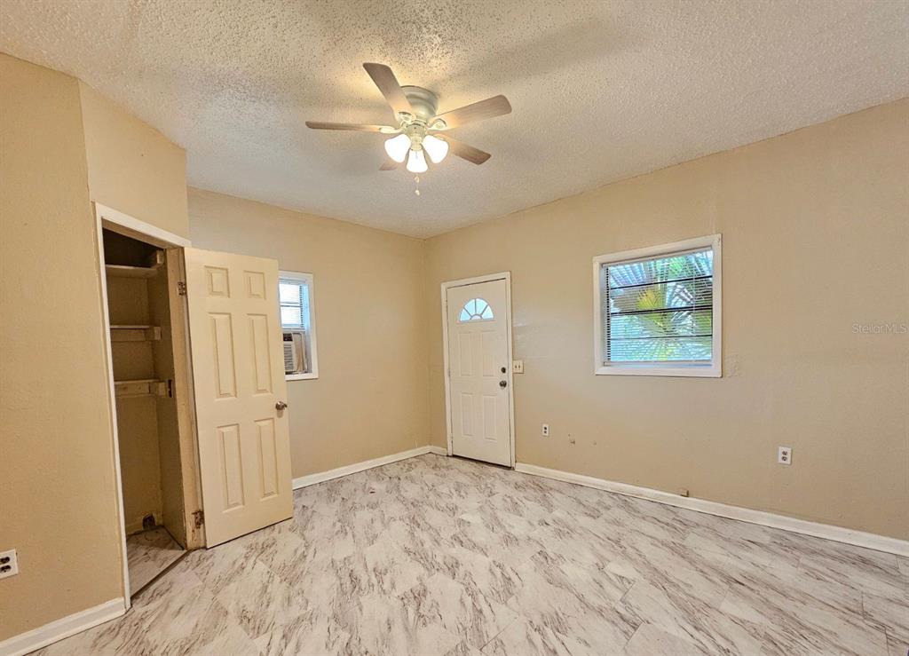 A bedroom with beige walls, a ceiling fan, a closet, and light-colored marble-patterned flooring — 1504 E 99TH AVENUE UNIT C, TAMPA, FL