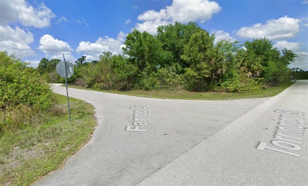 A street intersection shows a paved road with a stop sign and dense vegetation — S TORRINGTON STREET, NORTH PORT, FL