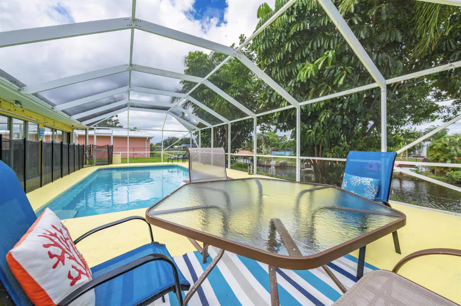 A screened-in patio features a swimming pool, a glass-top dining table, and outdoor seating — PORT ST. LUCIE, FL