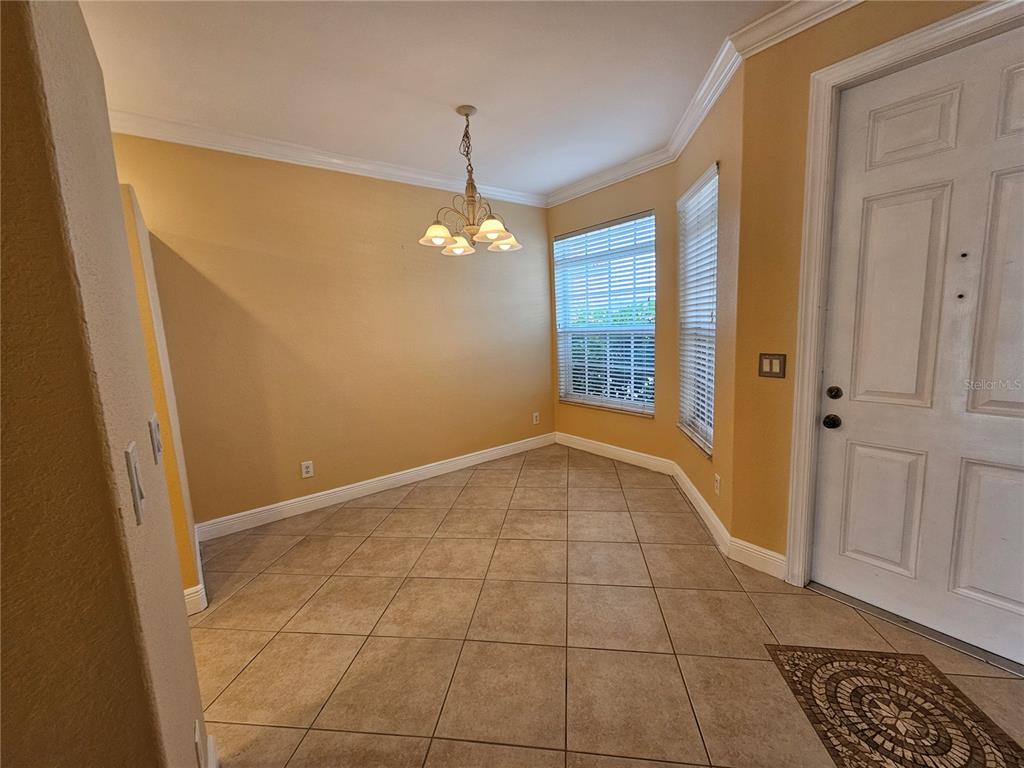 A dining area with tan walls, tile flooring, a chandelier, and a white front door — 231 CULTURAL PARK BOULEVARD S UNIT B, CAPE CORAL, FL