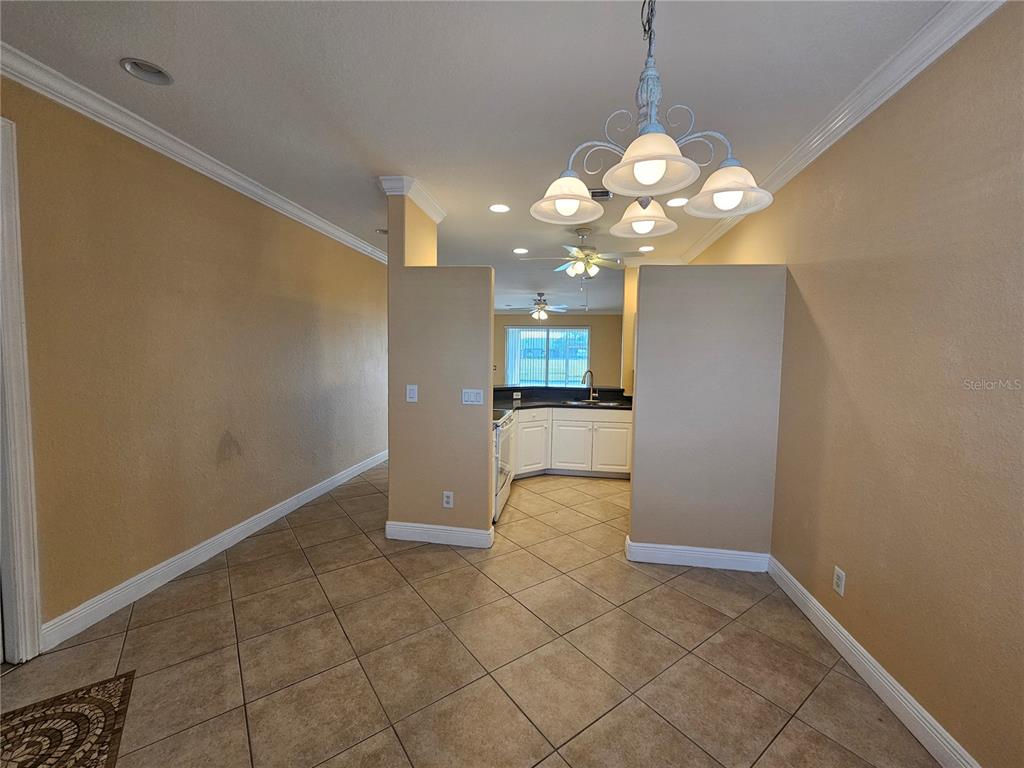 A dining area with tile flooring leads into a kitchen with white cabinets and counters — 231 CULTURAL PARK BOULEVARD S UNIT B, CAPE CORAL, FL