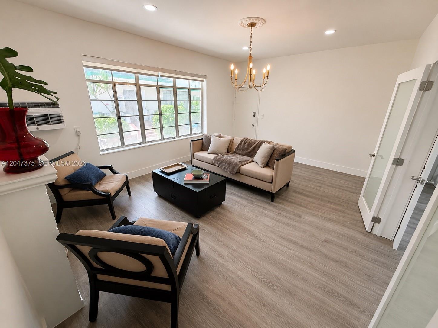 A living room features light wood flooring, a beige sofa, two armchairs, and a chandelier — 762 Lenox Ave # 2, Miami Beach FL 33139, MIAMI BEACH, FL