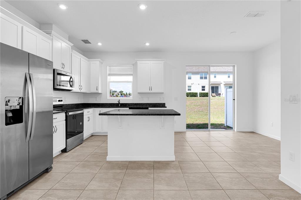 A kitchen with white cabinets, dark granite countertops, stainless steel appliances, and tile flooring — 1100 LAKESHORE BREEZE PLACE, KISSIMMEE, FL