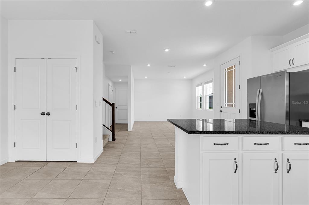 A kitchen with white cabinets and a granite island overlooks an open living area — 1100 LAKESHORE BREEZE PLACE, KISSIMMEE, FL