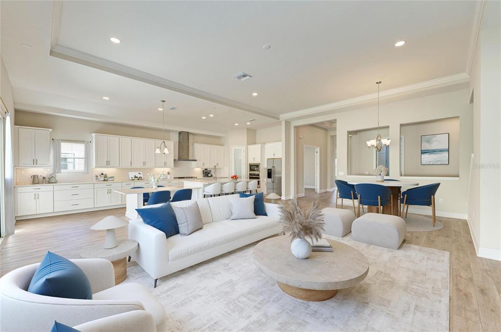 An open-concept living room and kitchen featuring white cabinetry, a large sofa, and dining area — 13068 HOMESTEAD LANE, PARRISH, FL