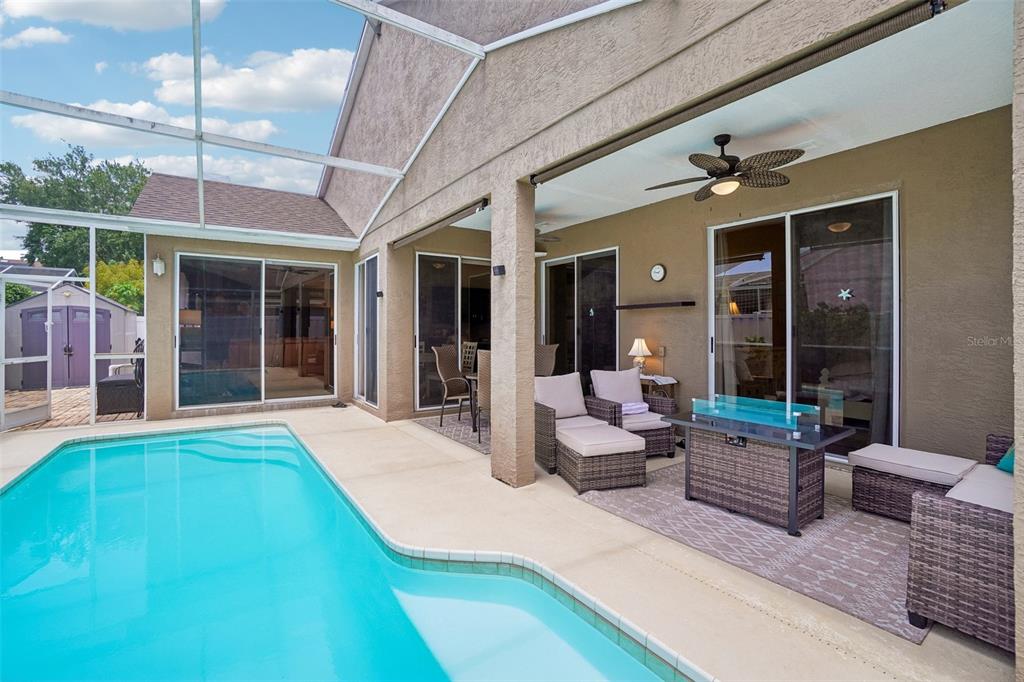 A covered patio with outdoor furniture and a ceiling fan overlooks a private swimming pool — 1817 WOOD BEND STREET, TARPON SPRINGS, FL