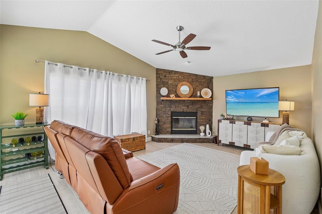 A living room features a stone fireplace, a brown leather sofa, and a white sofa — 1817 WOOD BEND STREET, TARPON SPRINGS, FL