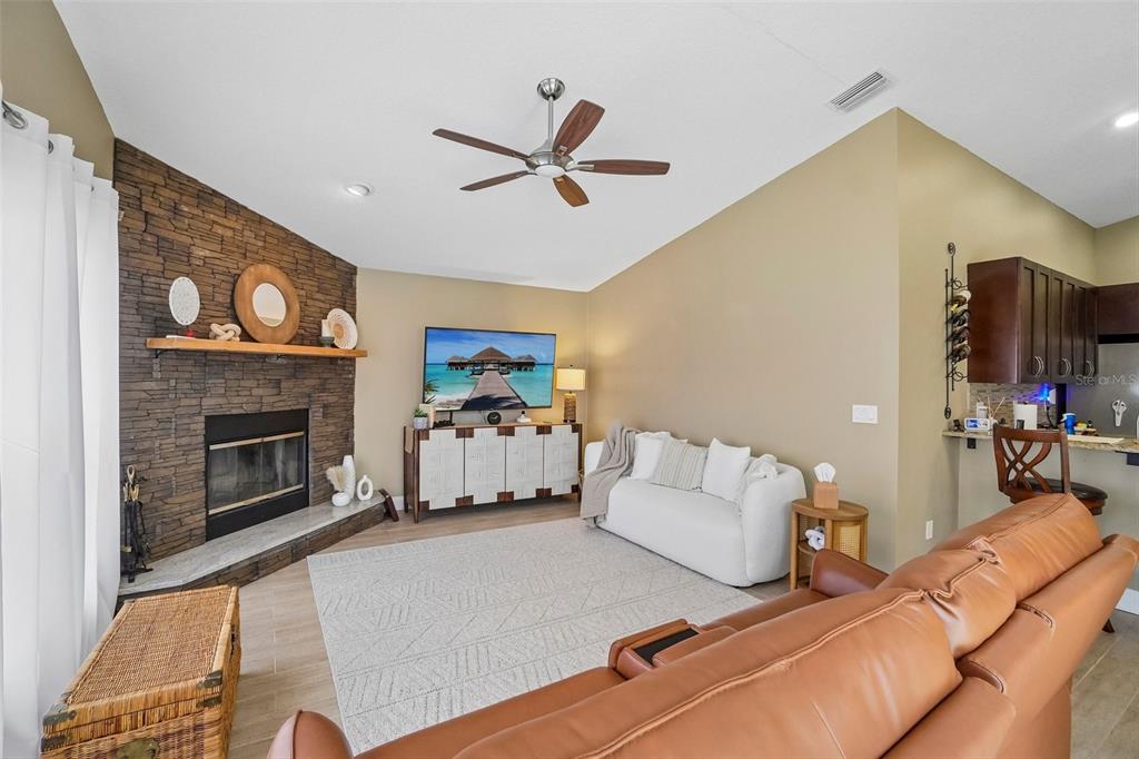 A living room features a stone fireplace, a white sofa, and a brown leather couch — 1817 WOOD BEND STREET, TARPON SPRINGS, FL