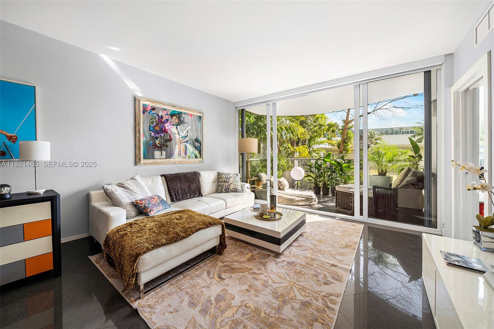 A living room features a white sectional sofa, a coffee table, and a glass balcony door — 2155 Washington Ct # 205, Miami Beach FL 33139, MIAMI BEACH, FL