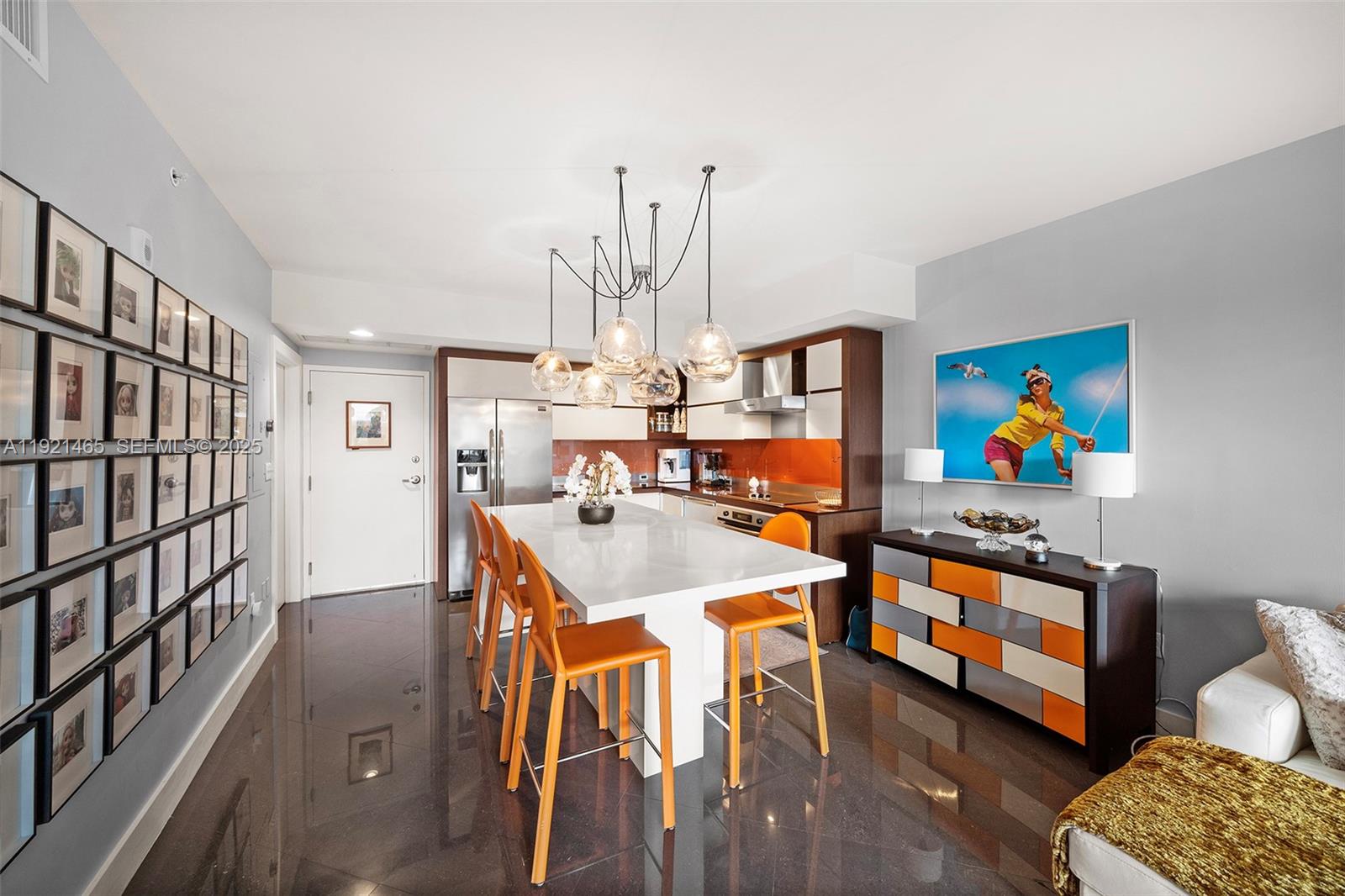 A modern kitchen features a white island, orange bar stools, and a dark tile floor — 2155 Washington Ct # 205, Miami Beach FL 33139, MIAMI BEACH, FL