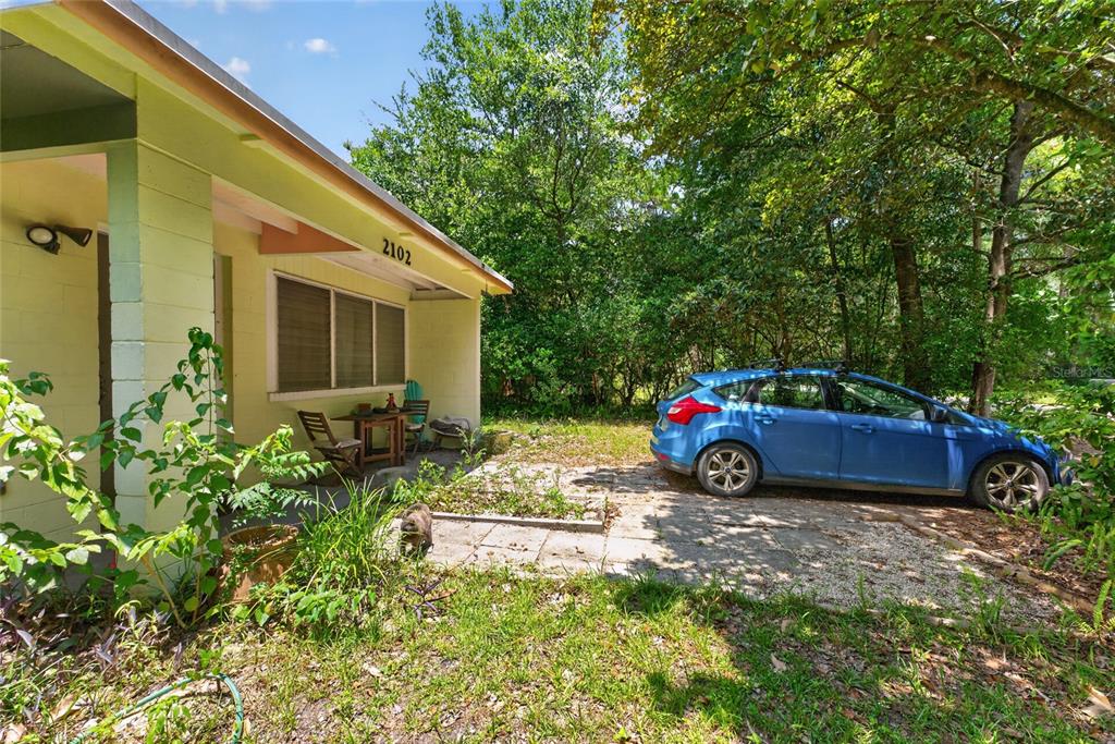 A light green house exterior features a small patio with furniture and a parked car — 2102 NE 8TH STREET, GAINESVILLE, FL