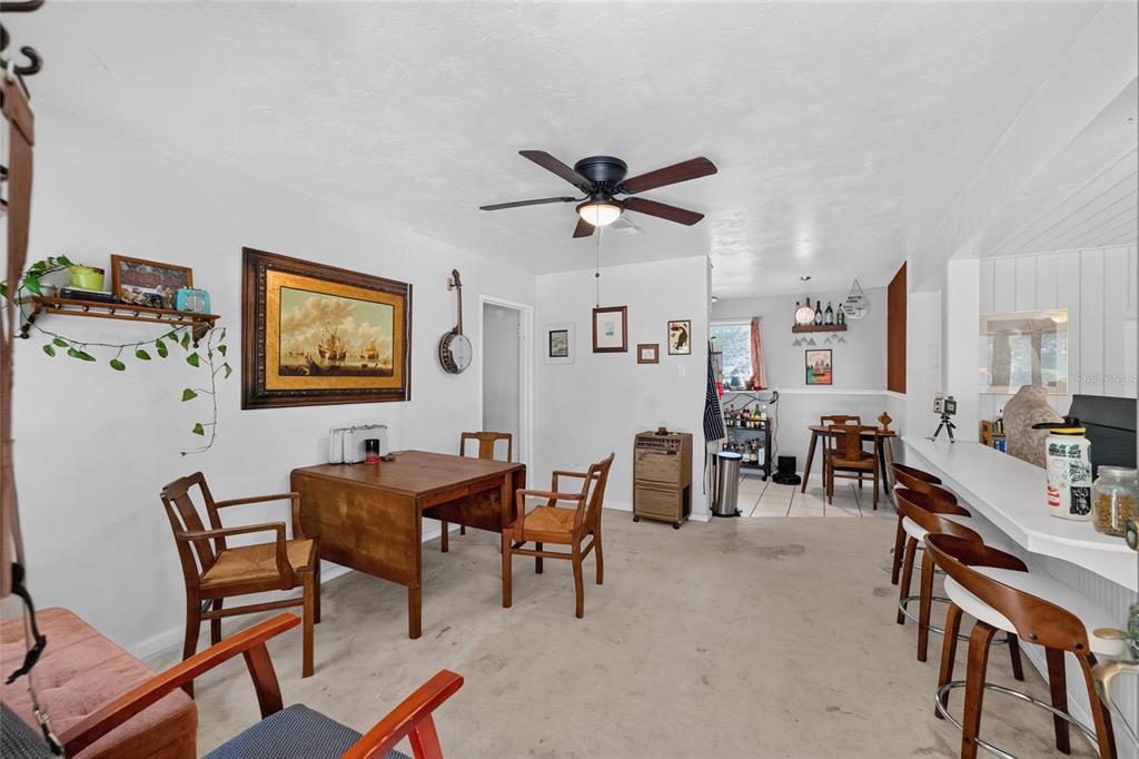 A dining area with a wooden table, chairs, a ceiling fan, and a breakfast bar — 2102 NE 8TH STREET, GAINESVILLE, FL