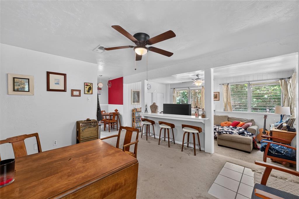 A dining area opens into a living room with a breakfast bar and carpeted floors — 2102 NE 8TH STREET, GAINESVILLE, FL