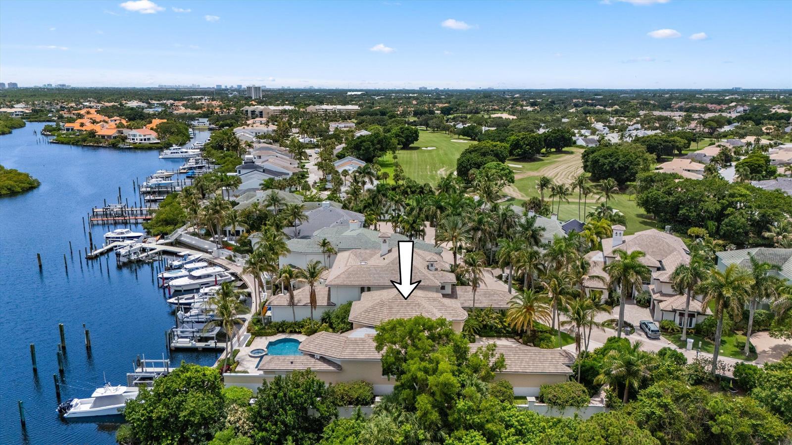 An aerial view shows a waterfront house with a pool, boat dock, and tiled roof — 3551 Jonathans Harbour Drive, Jupiter FL 33477, JUPITER, FL