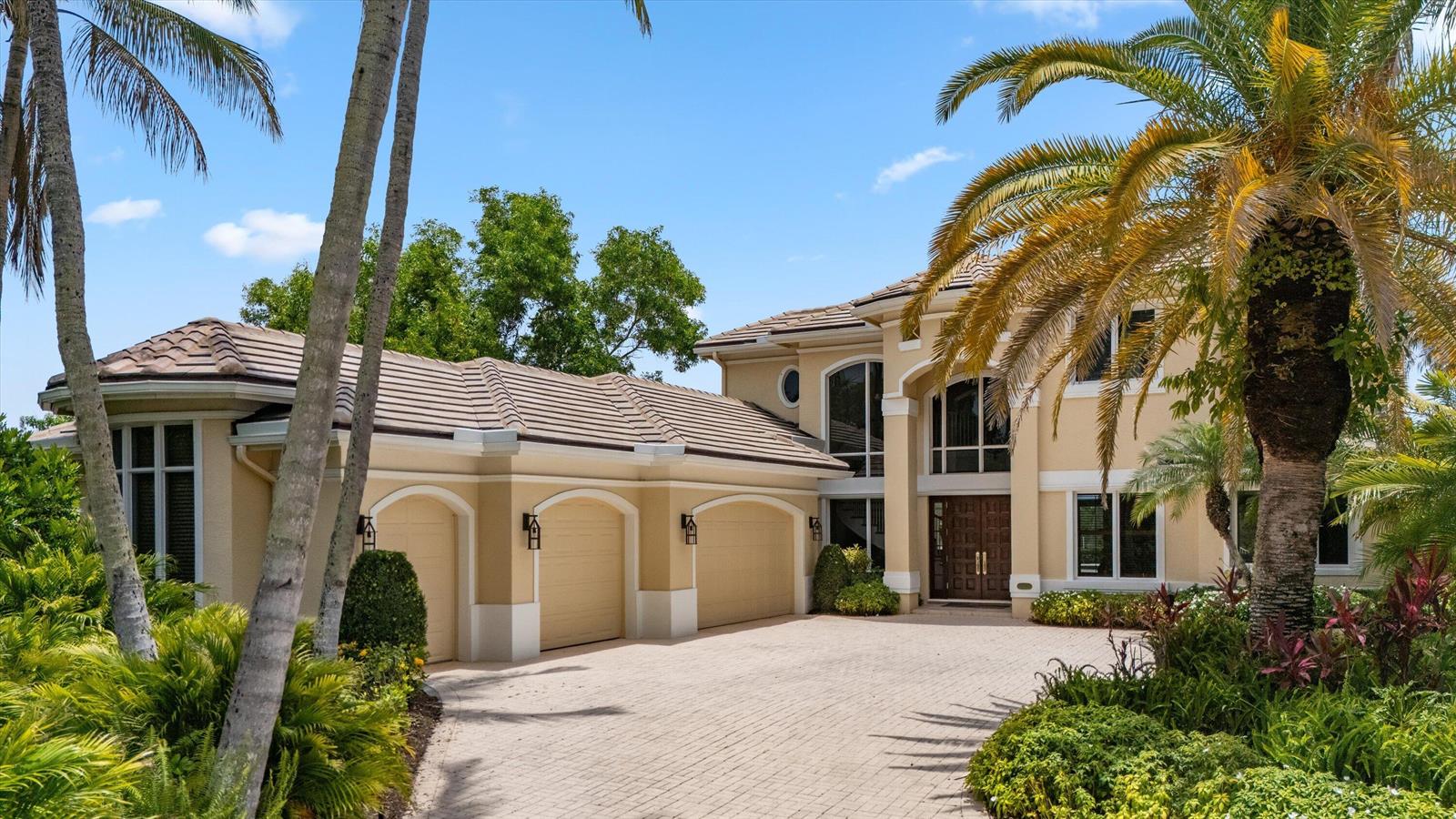 A two-story beige house with a three-car garage and a paved driveway surrounded by palms — 3551 Jonathans Harbour Drive, Jupiter FL 33477, JUPITER, FL