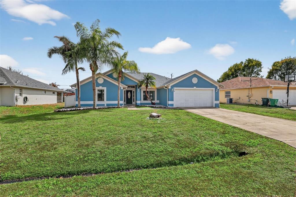 A blue single-story house with a two-car garage and palm trees in the front yard — 566 SW SEA HOLLY TERRACE, PORT ST LUCIE, FL