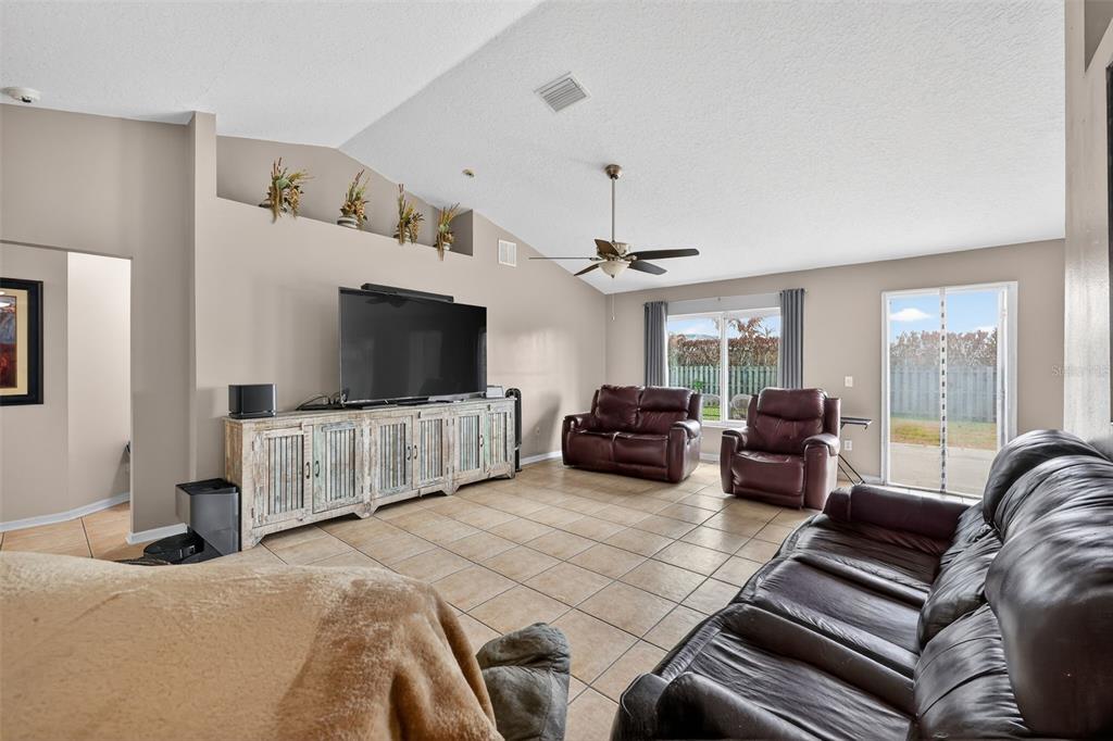 A living room features tile flooring, a vaulted ceiling, a television console, and leather furniture — 566 SW SEA HOLLY TERRACE, PORT ST LUCIE, FL