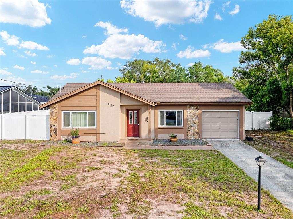 A single-story house with a brown roof, tan stucco exterior, and a one-car garage — 10196 HEATHCLIFF STREET, SPRING HILL, FL