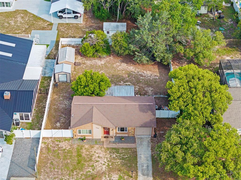 An aerial view shows a single-story house with a brown roof, driveway, and large backyard — 10196 HEATHCLIFF STREET, SPRING HILL, FL