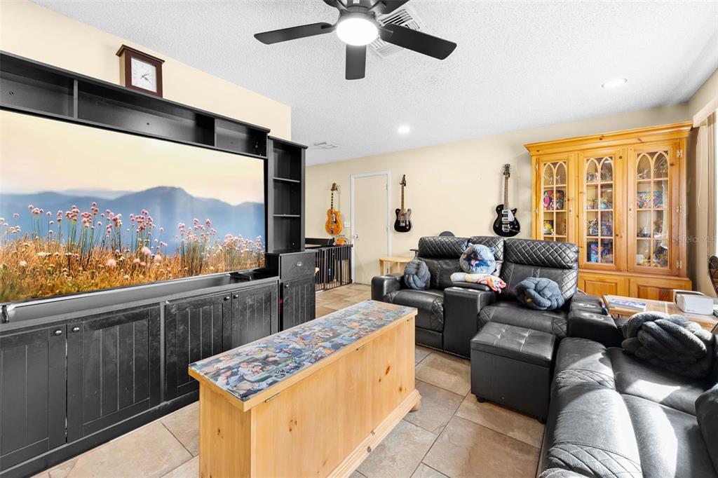 A living room features a large entertainment center, black leather recliners, and a wooden console — 10196 HEATHCLIFF STREET, SPRING HILL, FL