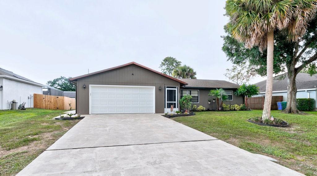 A single-story house with a brown exterior, a two-car garage, and a concrete driveway — SEBASTIAN, FL