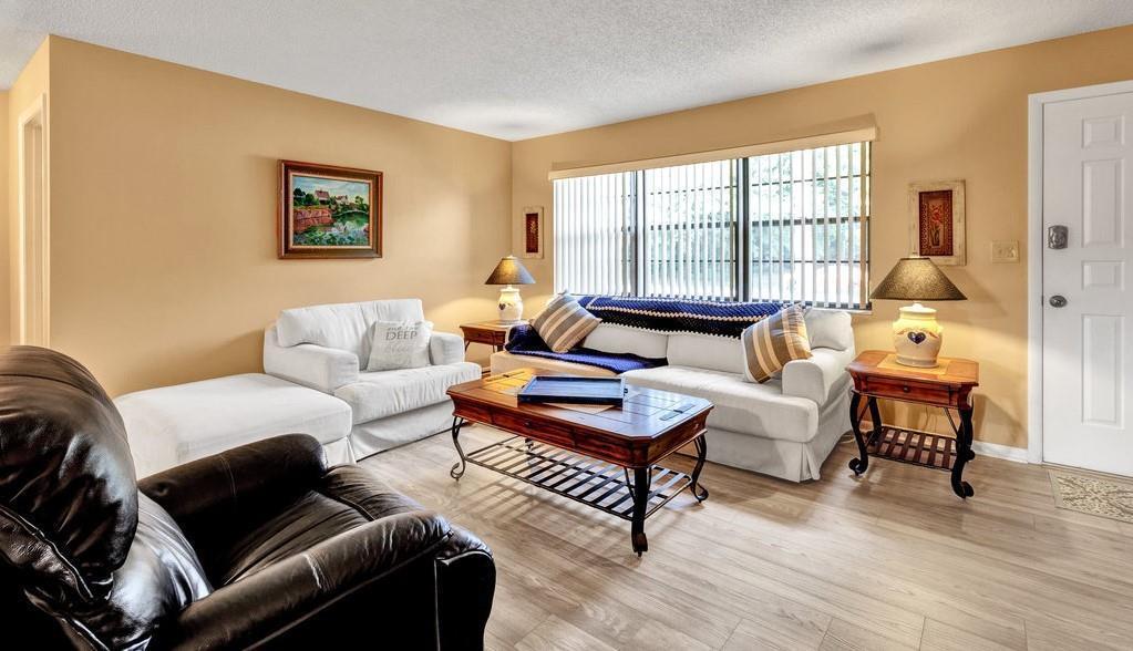 A living room features light-colored walls, wood-look flooring, a white sofa, and a dark leather armchair — SEBASTIAN, FL