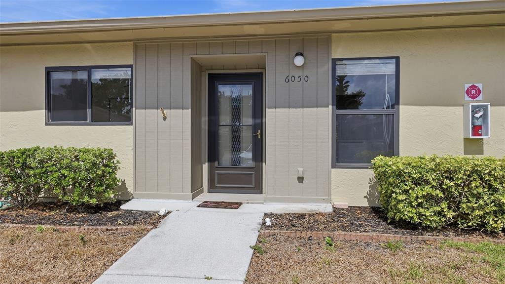 The exterior of a single-story building features a central front door, windows, and landscaping — 6050 28TH STREET W, BRADENTON, FL