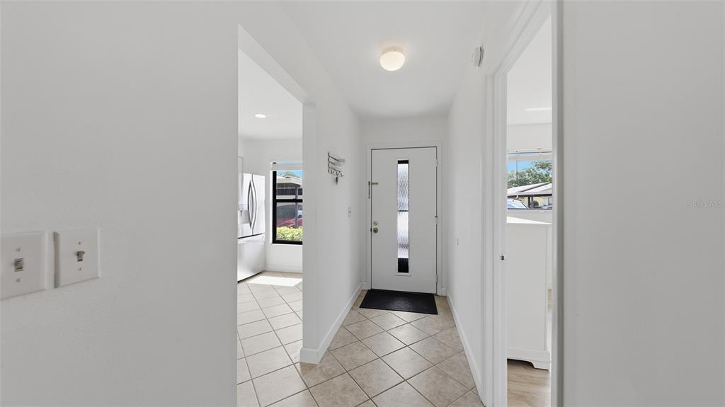 A bright entryway features white walls, tile flooring, a front door, and adjacent room openings — 6050 28TH STREET W, BRADENTON, FL