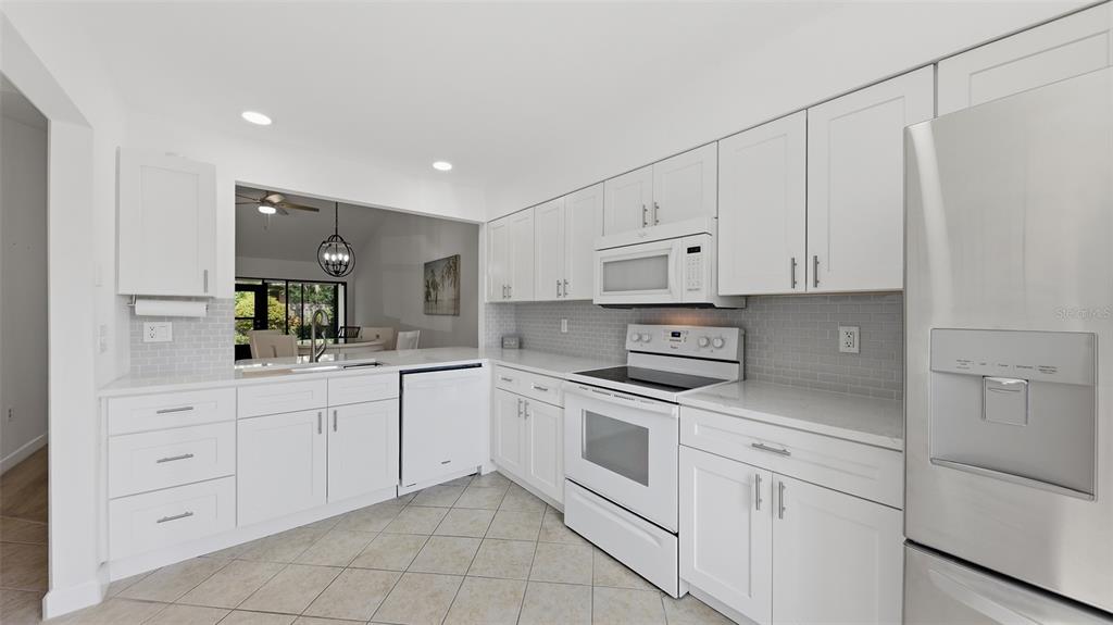 A white kitchen features stainless steel appliances, white cabinetry, and a light-colored tile floor — 6050 28TH STREET W, BRADENTON, FL