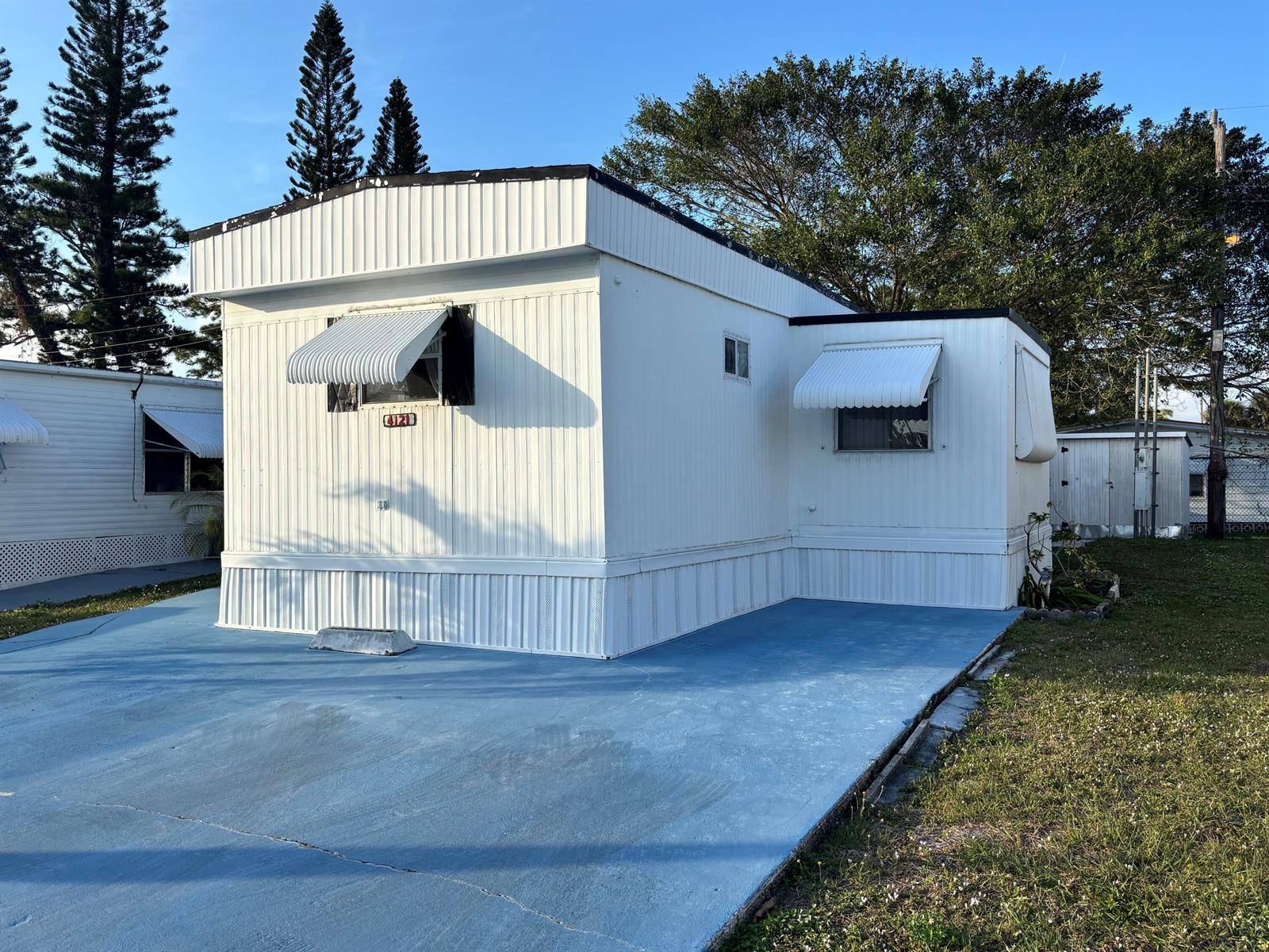 A white mobile home with a blue concrete driveway and metal window awnings — 4121 88th Court S, Boynton Beach FL 33436, BOYNTON BEACH, FL