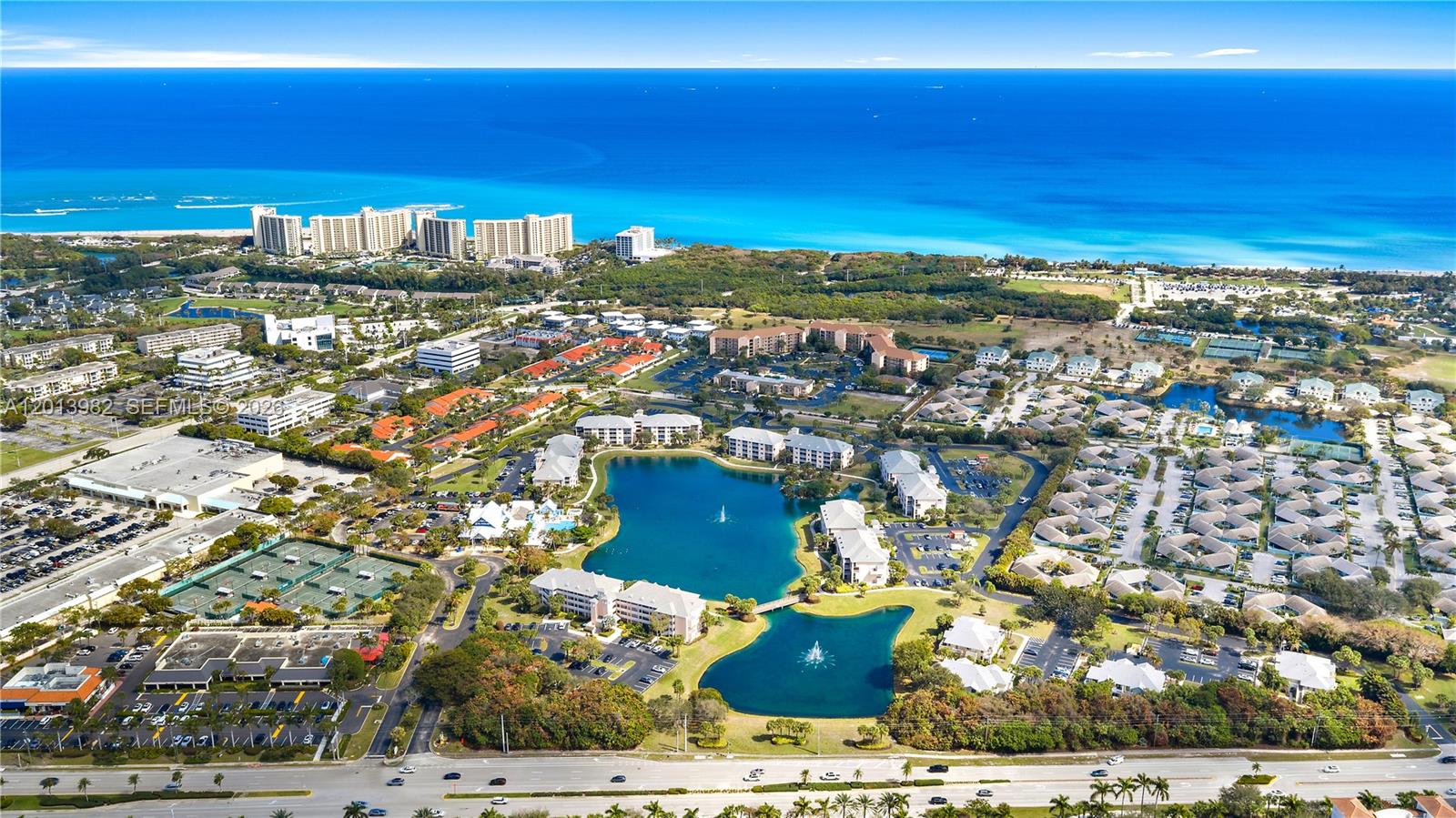 An aerial view shows a residential complex with two lakes, tennis courts, and nearby oceanfront buildings — 275 Palm Ave # A205, Jupiter FL 33477, JUPITER, FL